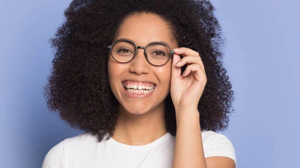 Sonriendo chica afroamericana en gafas mira a la cámara riendo —  Fotos de Stock