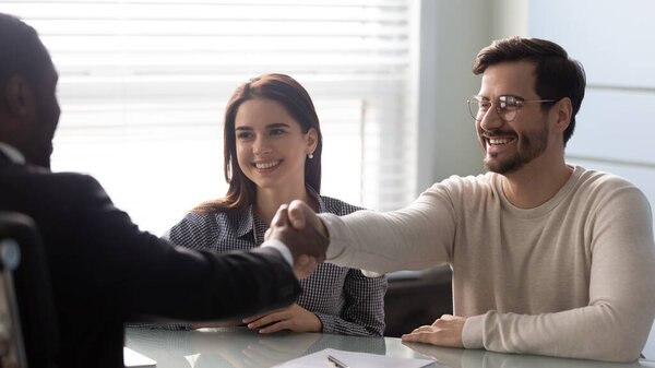Smiling young man shaking hands with financial advisor.