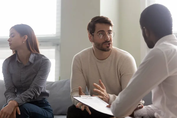 Joven mujer insatisfecha aburriéndose mientras su marido habla con el psicólogo . — Foto de Stock