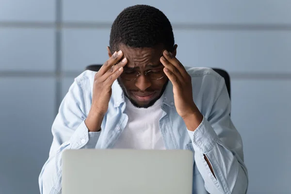 Overwhelmed exhausted young worker suffering from strong head pain. — Stock Photo, Image