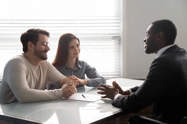 Smiling african american male banker consulting young married couple. — Stok Foto