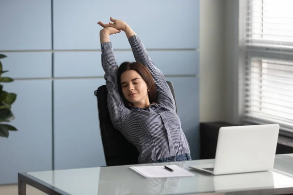 Satisfeito com o trabalho feito jovem gerente do sexo feminino que se estende de volta . — Fotografia de Stock