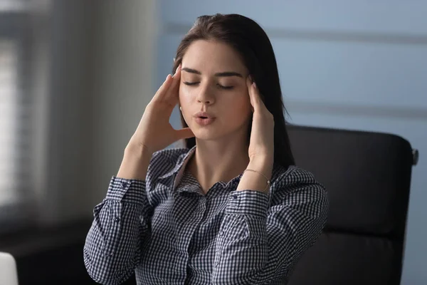 Mulher estressada massageando templos, tentando controlar a pressão de trabalho no escritório . — Fotografia de Stock