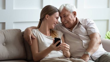 Yaşlı büyükbaba ve yetişkin torun eğleniyor cep telefonu kullanıyor.