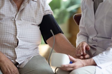 Hemşire 70 'lerin kan basıncını sfenometre yakın çekim görüntüsü kullanarak ölçüyor.