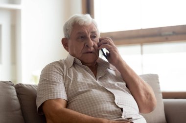 Yaşlı adam doktorla uzaktan iletişim kurarak telefonda konuşuyor.