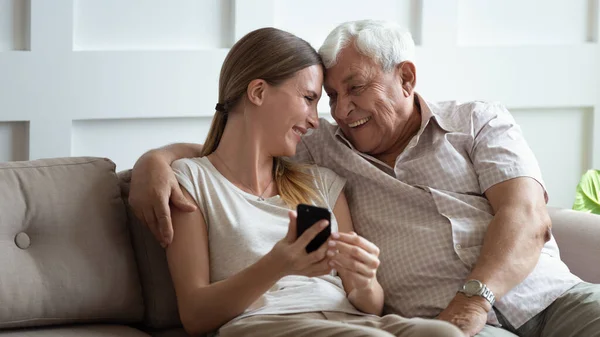 Elderly grandfather and adult granddaughter having fun use mobile phone — Stock Photo, Image