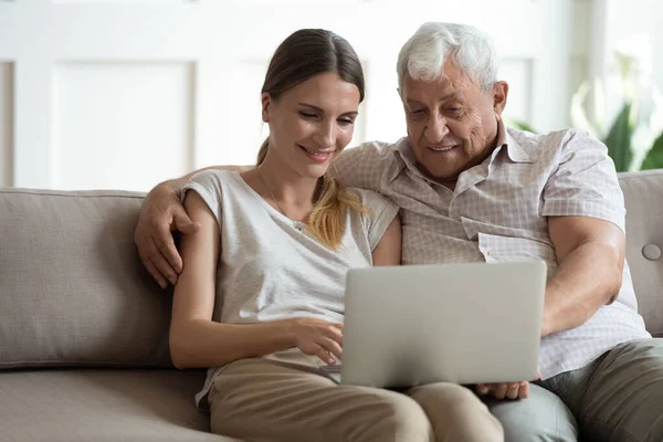 Grandfather and adult granddaughter spend time together use laptop — Stock Photo, Image