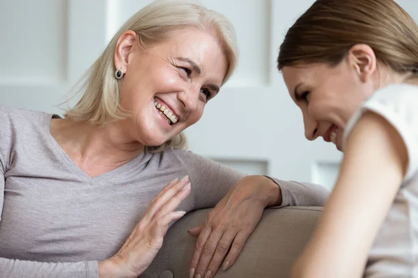 Allegro madre anziana ridendo parlando con figlia cresciuta al chiuso — Foto Stock