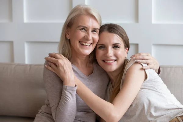 Feliz anciana madre e hija adulta tomados de la mano abrazando en el interior — Foto de Stock