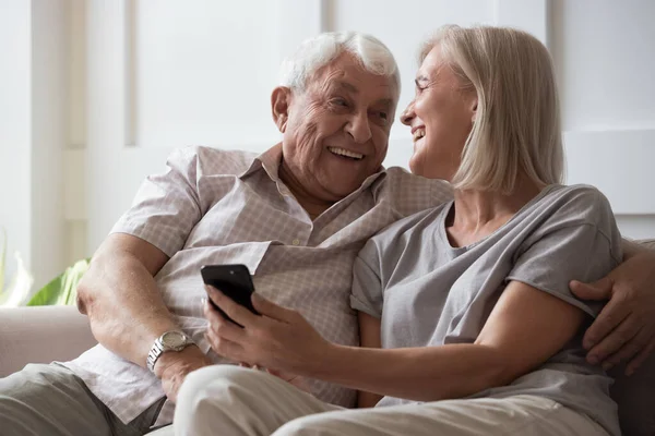 Elderly husband and middle-aged wife having fun using smartphone — Stock Photo, Image