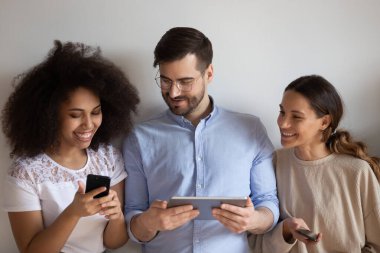 Mutlu çeşitli arkadaşlar birlikte cep telefonu oyunu oynuyorlar, cihazlar kullanıyorlar.