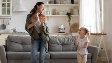 Mutlu anne ve tatlı küçük kız oturma odasında dans ediyor.