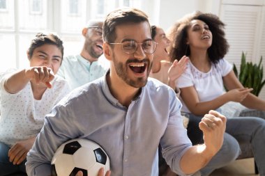 Heyecanlı adam golü kutluyor, çeşitli arkadaşlarla futbol seyrediyor.