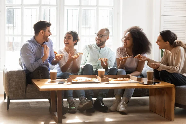 Felices amigos diversos comiendo pizza, hablando, divirtiéndose en la fiesta — Foto de Stock