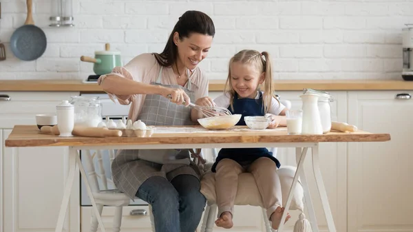Felice madre e piccola figlia che cucinano a tavola in cucina — Foto Stock