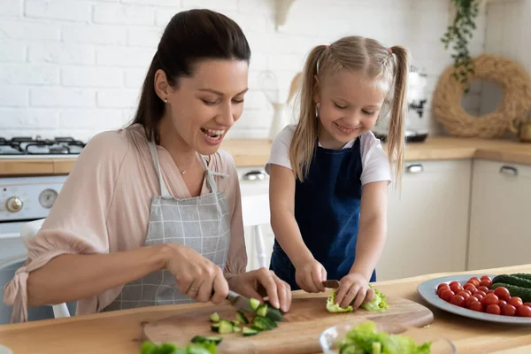 Mutlu anne ve küçük kız önlük giyip birlikte yemek pişiriyorlar. — Stok fotoğraf