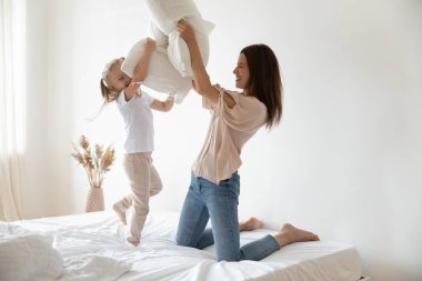 Mutlu anne ve küçük kız birlikte eğleniyor, yastık savaşı yapıyor