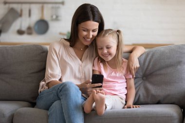 Mutlu genç anne ve küçük kızı birlikte telefon kullanıyor.