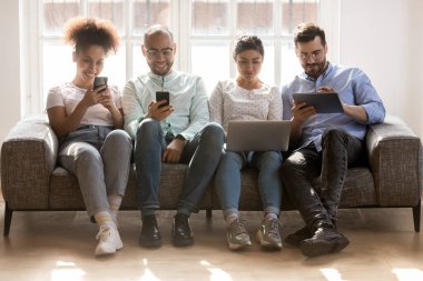 Çeşitli gençler elektronik cihazlar kullanıyor, sıra sıra oturuyorlar