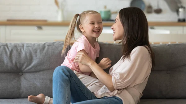 Gelukkig moeder en klein meisje hebben plezier, ontspannen op de bank — Stockfoto