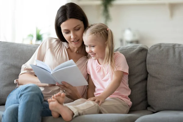 Madre amorosa enseñando a su hijita a leer en casa —  Fotos de Stock