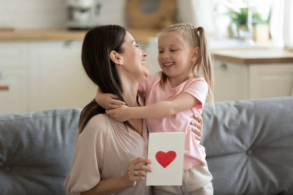 Glückliche Mutter umarmt kleine Tochter und bedankt sich für Geschenk-Postkarte — Stockfoto