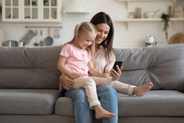 Щаслива молода мати і маленька дочка розважаються з телефоном — стокове фото