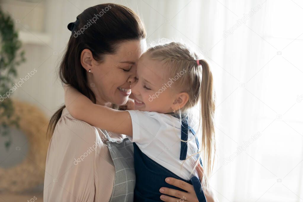 Happy loving mother holding little daughter, enjoying tender moment