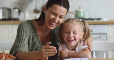 Mutlu anne ve kız evde akıllı telefon kullanarak gülüyorlar.