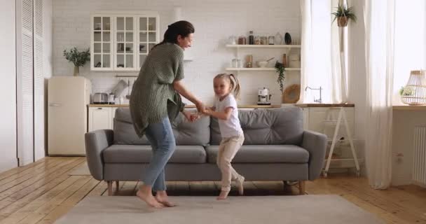 Feliz mamá y su hija bailando saltando juntos en la cocina — Vídeos de Stock