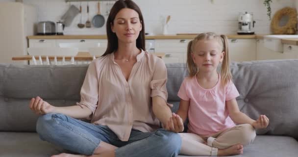 Saludable feliz mamá enseñando niño hija meditando sentarse en sofá — Vídeo de stock