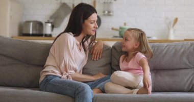 Mutlu genç anne ve küçük kız konuşuyor. Kanepeye otur.