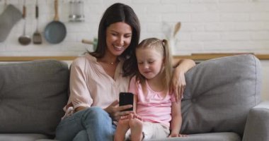 Mutlu anne ve çocuk kanepe üzerinde akıllı telefon kullanmaktan zevk alıyor.