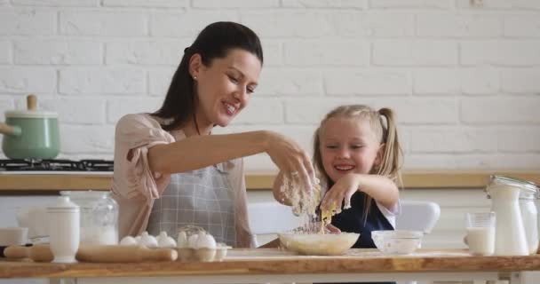 Cute kid daughter learning kneading dough with mom in kitchen — Stock Video