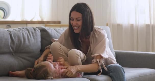 Boldog fiatal anya játszik aranyos gyerek lánya kanapén — Stock videók