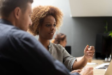 Erkek meslektaşı ile birlikte çalışan Afrikalı kadın çalışma alanında oturuyor.