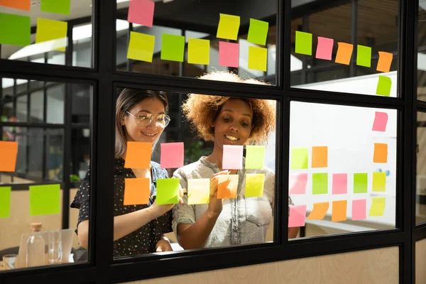 Multi donne d'affari razziali scrivere su appiccicoso note nuove idee di avvio — Foto Stock