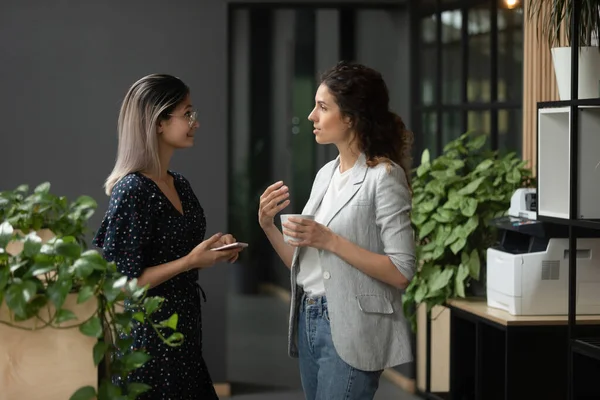 Businesswomen discuss project standing in workplace hall during coffee break — Stock Photo, Image
