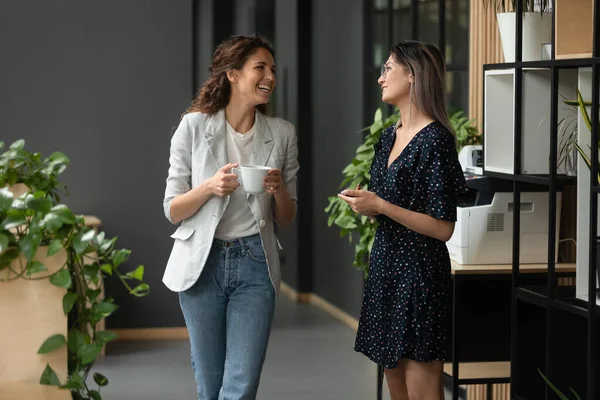 Asian and Caucasian ethnicity women colleagues chatting in office hallway — Stock Photo, Image