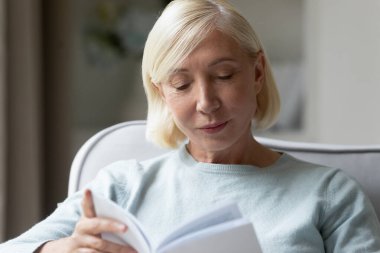 Yetişkin bir kadının kitap okuduğu portreyi yakından çek..