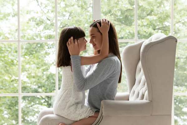 Liebevolle junge Mama hält kleine entzückende Tochter auf dem Schoß. — Stockfoto