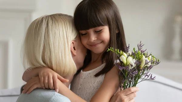 Little cute schoolgirl embracing middle aged grandmother. — Stok fotoğraf