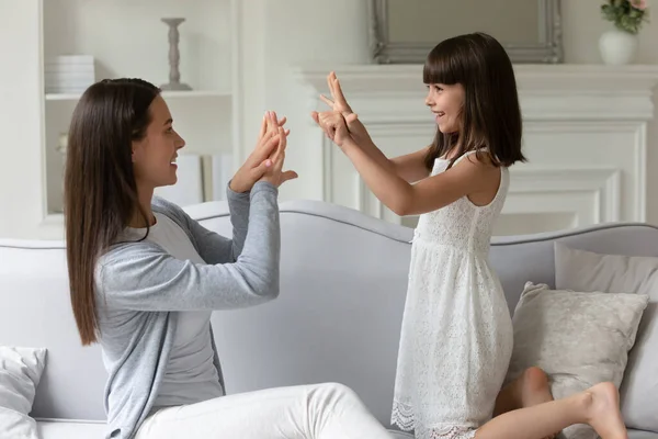 Petite fille mignonne d'âge scolaire jouant avec une jeune mère souriante . — Photo