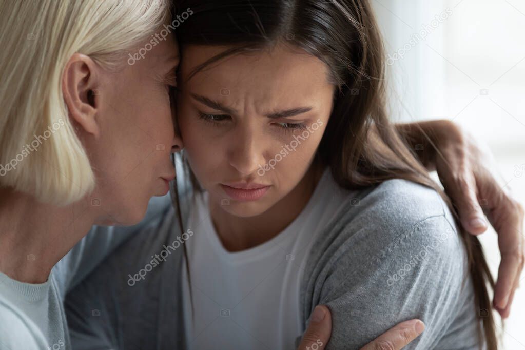 Empathic middle aged woman hugging upset daughter.
