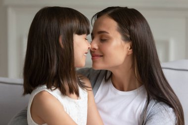 Cute preschool little girl touching noses with affectionate young mother. clipart