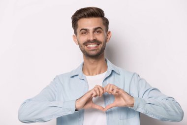 Gülümseyen adam kameraya bak, elleriyle kalbi göster.