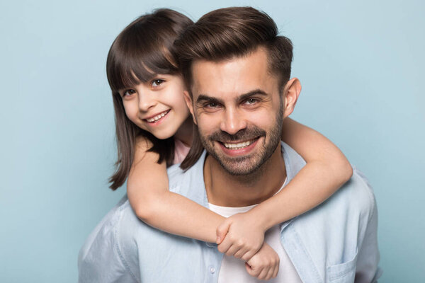 Улыбающаяся маленькая девочка обнимает молодого отца позируя для фото
