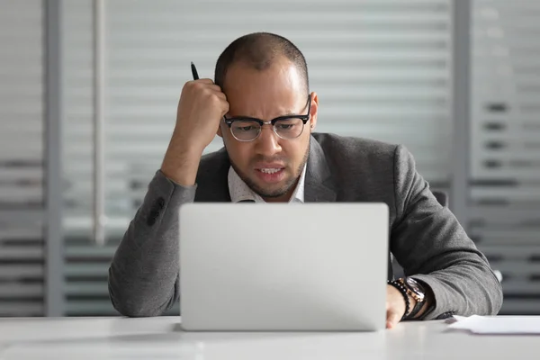 Несчастный афроамериканский бизнесмен смотрит на экран ноутбука — стоковое фото