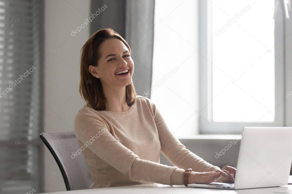 Portrait of happy laughing businesswoman working on laptop in office